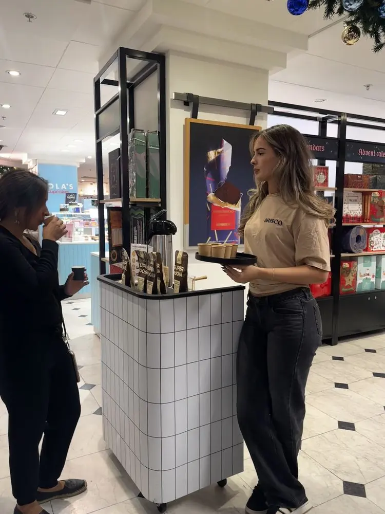 Sampling stand in a department store with a customer tasting a sample