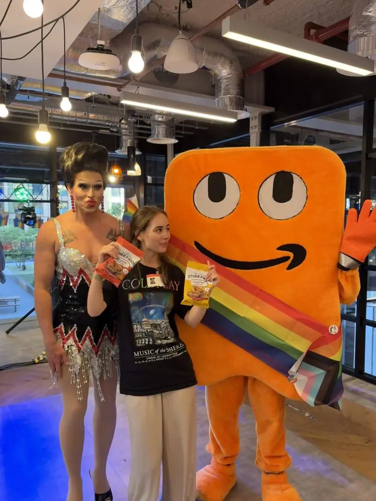 Event photo with a large orange mascot wearing a rainbow sash
