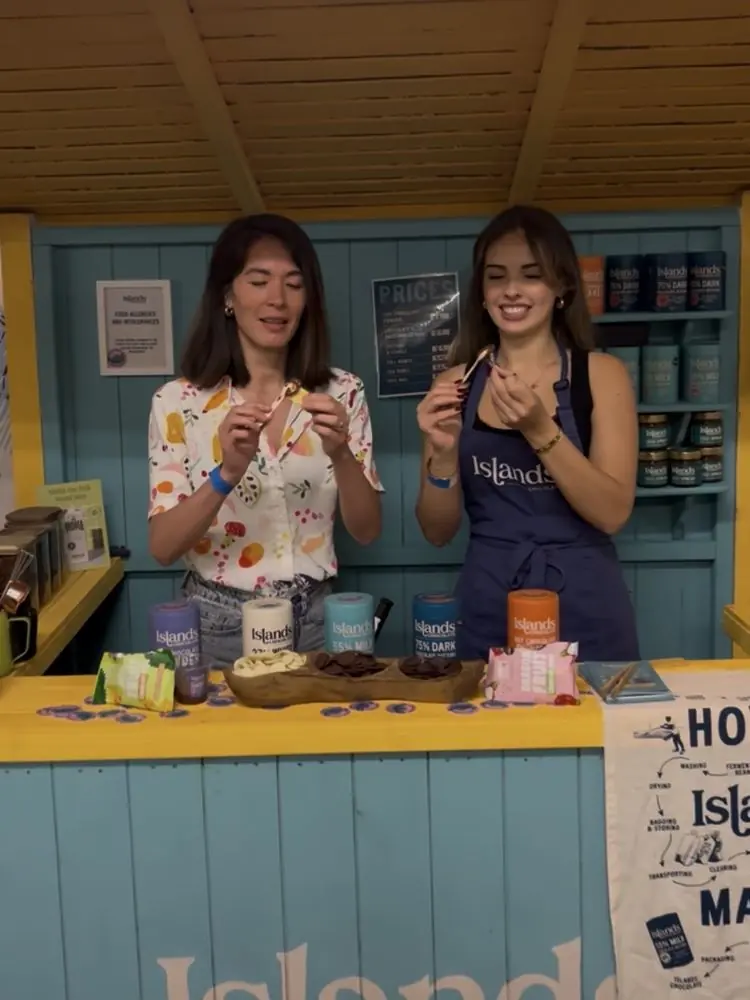 Two women tasting chocolate samples at the Islands Chocolate stand