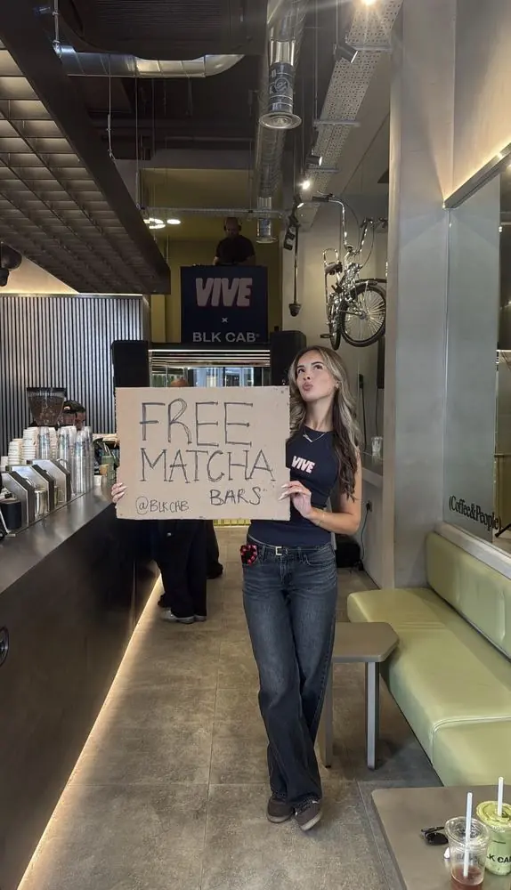 Katrina holding a Free Matcha Bars sign at the Vive x BLK CAB coffee shop activation